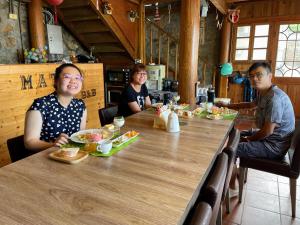 un grupo de personas sentadas en una mesa con comida en Matsu Seaside View Homestay, en Nangan