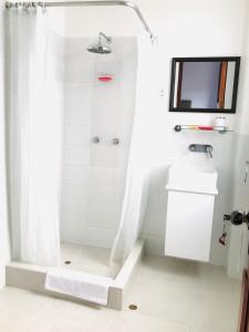 a white bathroom with a shower and a sink at Larq'a Park Rooms in Lima +43 photos
