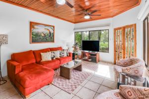 a living room with a red couch and a flat screen tv at Casa de Somer in Esterillos