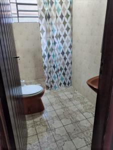 ein Bad mit einem WC und einem Duschvorhang in der Unterkunft Ohana Casa 2 Boraceia in Bertioga