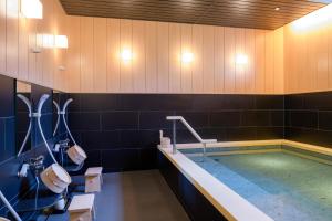 Tosei Hotel Cocone Kamakura في كاماكورا: حمام به مسبح وحوض استحمام