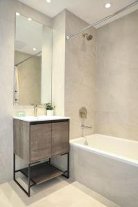 La salle de bains est pourvue d'un lavabo, d'une baignoire et d'un miroir. dans l'établissement Global Luxury Suites at The Arches, à Bronx