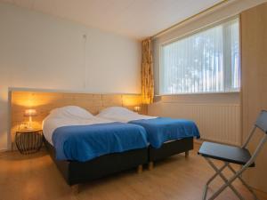 een slaapkamer met een bed, een stoel en een raam bij By Romme in Diessen