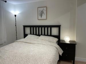 een slaapkamer met een bed en een nachtkastje met een lamp bij MT house in Mississauga