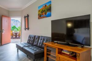 sala de estar con sofá de cuero negro y TV de pantalla plana en Wildflower Inn at Bell Rock, en Sedona