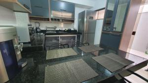 a kitchen with a black counter top with chairs in it at Recanto do Mundaí - Apto 101 in Porto Seguro