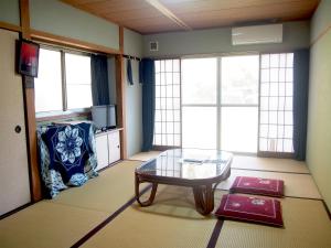 a living room with a glass table and a couch at Yukinoura Guest House Moritaya in Saikai