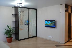トムスクにあるApartments on Uchebnaya st.のガラスのスライドドア(壁にテレビ付)が備わる客室です。