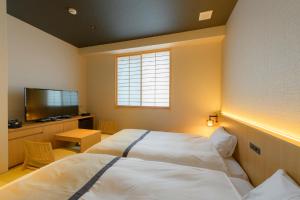 a bedroom with a white bed and a television at Tosei Hotel Cocone Kamakura in Kamakura