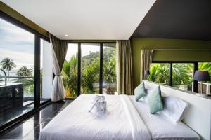 a bedroom with a large bed and large windows at See Sea Villa Phuket SHA in Patong Beach