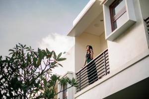 a woman standing on the balcony of a house at Musa Canggu in Canggu