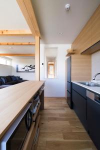 a kitchen with black cabinets and wooden counters at Furano Sanso in Furano