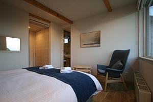 a bedroom with a bed and two chairs in it at Furano Sanso in Furano