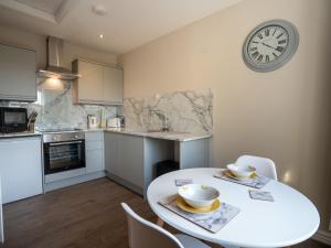 a kitchen with a white table and a clock on the wall at Hawthorn Cottage in Winston