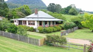 a white house with a fence in a yard at Magnolia Cottage Kangaroo Valley in Barrengarry