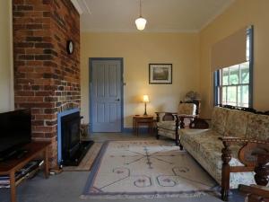 a living room with a couch and a brick wall at Magnolia Cottage Kangaroo Valley in Barrengarry