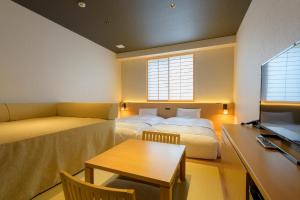 a room with two beds and a desk and a table at Tosei Hotel Cocone Kamakura in Kamakura