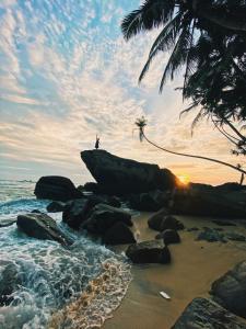 a person standing on a rock on the beach at Sri Gemunu Beach Resort in Unawatuna