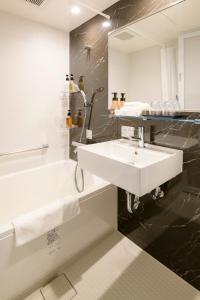 a bathroom with a white sink and a bath tub at Tosei Hotel Cocone Kamakura in Kamakura