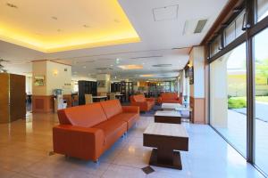 a lobby with orange couches and tables in a building at Fuji Matsuzono Hotel in Yamanakako