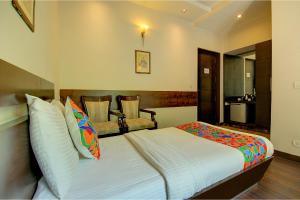 a bedroom with a bed and a chair at FabHotel Phoenix Hospitality Near DLF Cyber Hub & Metro, Gurugram in Gurgaon