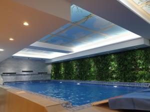 a large swimming pool with a green wall at Costa Del Sol Hotel by Arabian Link in Kuwait