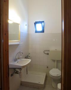 a bathroom with a sink and a toilet and a light at Thanasis Matsas Rooms in Kamariotissa