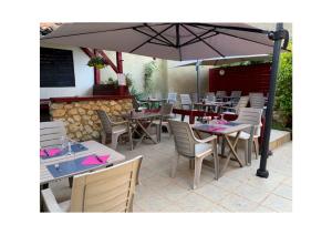 a restaurant with tables and chairs and an umbrella at Hôtel Restaurant de l'Union in Mirambeau