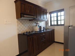 a kitchen with wooden cabinets and a counter top at Woodside Retreat- Serviced Apartments in Baga