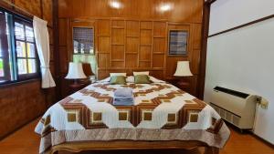 a bedroom with a bed and two lamps and windows at Hotel Siblanburi Resort in Mae Hong Son