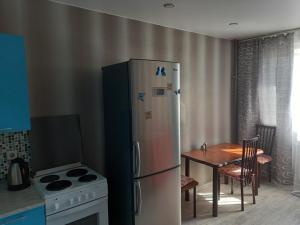 een keuken met een koelkast en een tafel en een stoel bij Apartments 30 micro-district, 9 in Angarsk