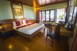 a bedroom with a bed and a desk and window at Rocky Point Resort in Thap Sakae