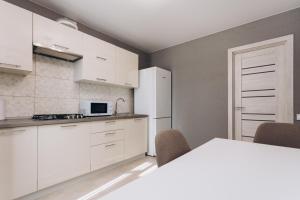 - une cuisine avec des placards blancs, une table et des chaises dans l'établissement Apart Lux Lavina, à Soumy