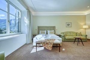 een slaapkamer met een bed en een bank bij Villa Tell rooms and suites in Merano +63 foto's