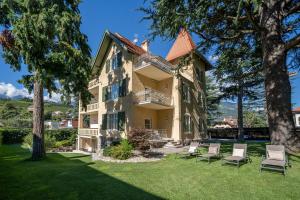 a large house with chairs on a lawn at Villa Tell rooms and suites in Merano