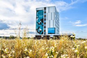 a tall glass building with a field in front of it at Hotel Das Zeit in Lenzing