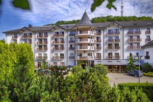 a large white building with a pointed roof at Hotel Verde Montana Wellness & Spa in Kudowa-Zdrój