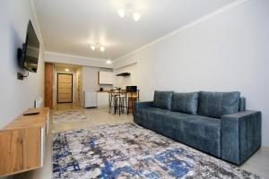 a living room with a blue couch and a kitchen at New and cozy studio in the best area! 4 in Almaty