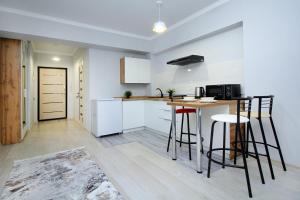 a kitchen with white cabinets and a table and stools at New and cozy studio in the best area! 4 in Almaty