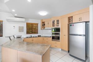una cocina con nevera de acero inoxidable y armarios en Meridien Beachfront Apartments at Trinity Beach, en Trinity Beach