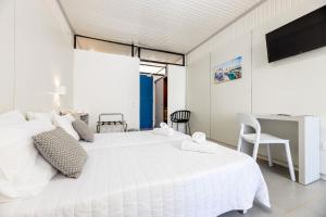 a white bedroom with a large white bed and a desk at Hippocampus Hotel in Naousa