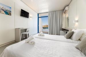a bedroom with two beds and a desk and a window at Hippocampus Hotel in Naousa