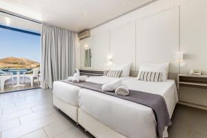 a white bedroom with a large bed and a balcony at Hippocampus Hotel in Naousa