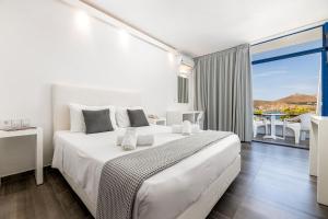 a white bedroom with a large bed and a balcony at Hippocampus Hotel in Naousa
