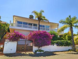 une maison avec des fleurs violettes devant une clôture dans l'établissement Villa Carioca - with private pool, marvelous garden and amazing ocean view, à El Sauzal