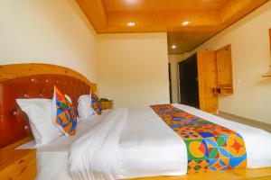 a bedroom with a large bed with a wooden headboard at FabHotel King XI Hospitalities in Manāli