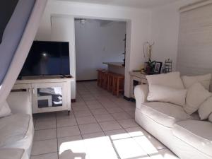 a living room with a white couch and a flat screen tv at Fourways Guest Lodge in Johannesburg