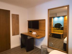 a room with a desk with a tv and a mirror at Hotel Holländer Hof in Meschede