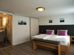 ein Schlafzimmer mit einem großen Bett mit lila Kissen in der Unterkunft Hotel Holländer Hof in Meschede