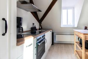 een keuken met witte kasten en een fornuis met oven bij Ferienwohnungen im Weingarten Quedlinburg in Quedlinburg